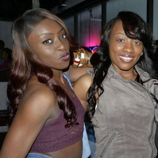 Two women posing for a photo at Empire Lounge, one with dark hair and a purple top, the other smiling.