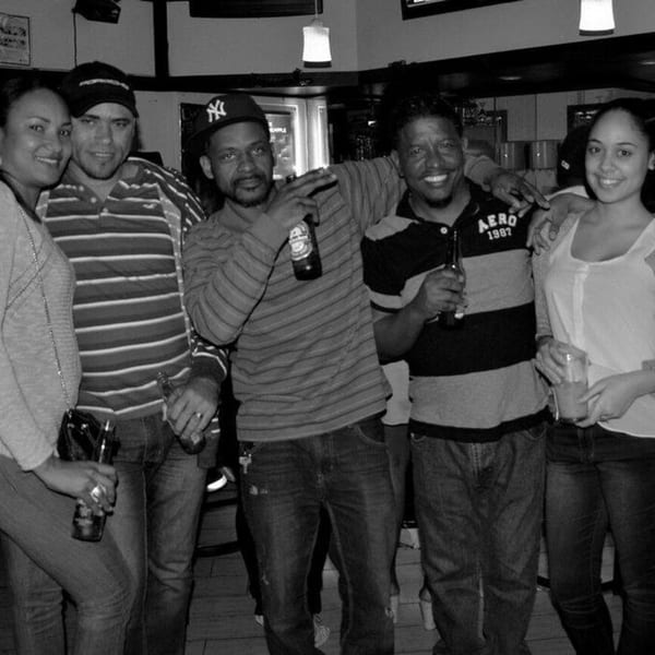 Five smiling people, three men and two women, enjoying drinks at Empire Lounge.