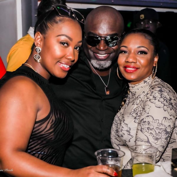 Three smiling people, two women and one man, enjoying drinks at Empire Lounge.