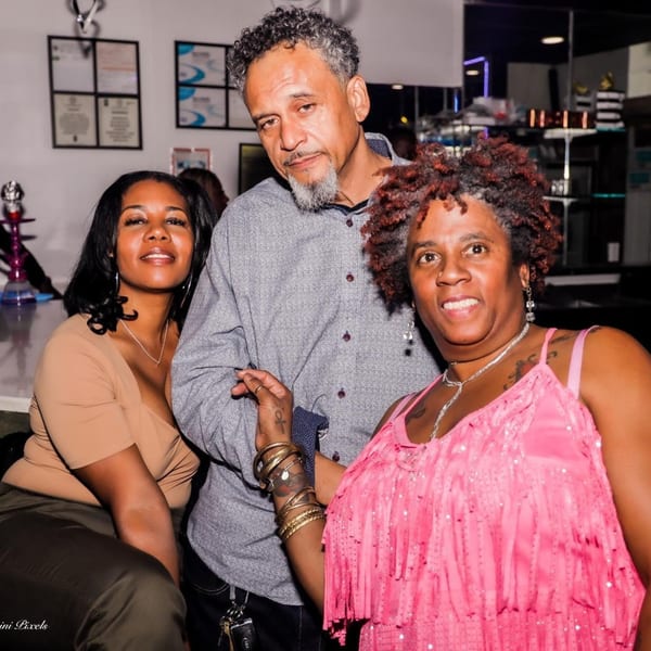 Three patrons, two women and one man, posing together at Empire Lounge bar.