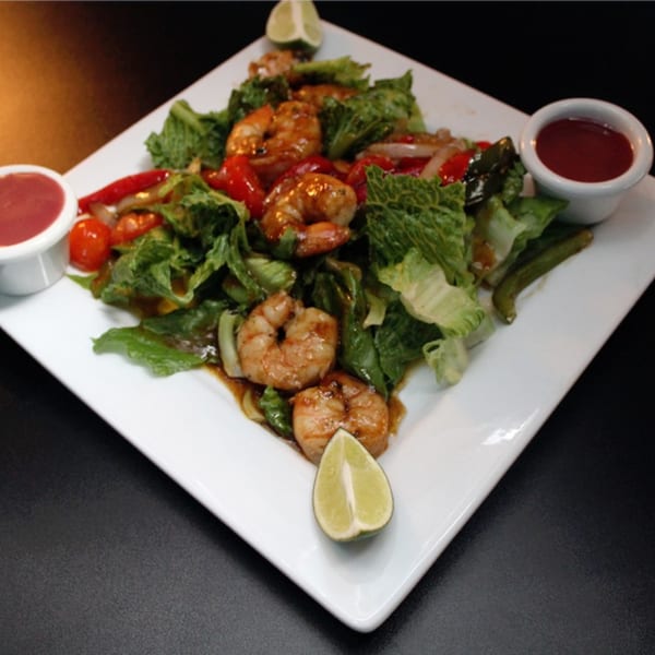 Empire Lounge's shrimp salad with lettuce, bell peppers, and two dipping sauces, garnished with lime.
